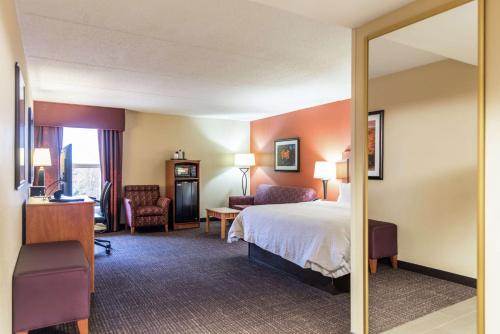 Habitación de hotel con cama y espejo en Hampton Inn Muskegon en Muskegon Heights