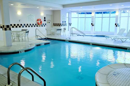 a swimming pool with blue water in a building at Hilton Garden Inn Westbury in Westbury