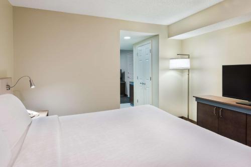 a bedroom with a large white bed and a flat screen tv at Hilton Garden Inn Westbury in Westbury