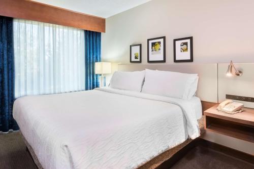 a hotel room with a large white bed and a phone at Hilton Garden Inn Westbury in Westbury