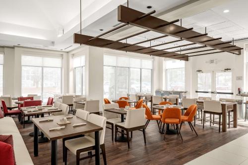 a restaurant with tables and chairs and windows at Hilton Garden Inn Raleigh Durham Airport in Morrisville