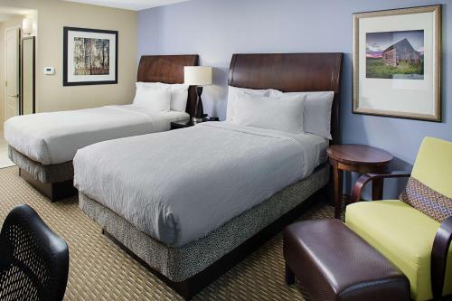 a hotel room with two beds and a chair at Hilton Garden Inn Raleigh Durham Airport in Morrisville