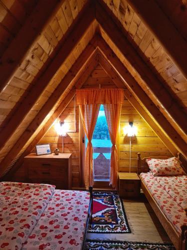 a attic room with two beds and a window at Nika in Nova Varoš