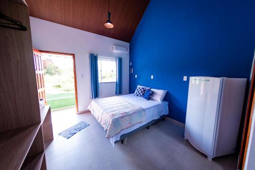 Cette chambre bleue comprend un lit et un réfrigérateur. dans l'établissement Flats 2 Locação Penedo RJ, à Penedo