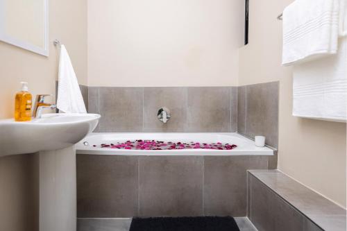y baño con bañera con flores rosas. en The Sunrise Waterfall, en Midrand