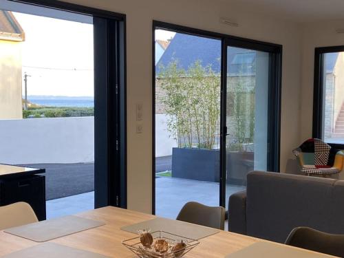 une salle à manger avec une table et une grande baie vitrée dans l'établissement Appartement RDC avec grande terrasse et parking, à Ploemeur