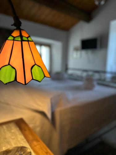 an orange and green stained glass lamp hanging over a bed at La Gazza Ladra House in Pieve di Carpegna