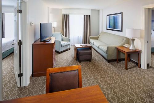 a living room with a couch and a tv in a hotel room at Homewood Suites by Hilton Raleigh/Cary in Cary