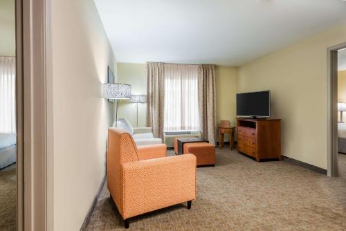 a hotel room with a chair and a television at Larkspur Landing Extended Stay Suites St Louis Riverport in Maryland Heights