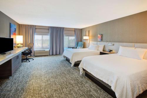 a hotel room with two beds and a flat screen tv at Hilton Garden Inn Chesterton in Chesterton