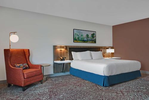 a hotel room with a bed and a chair at Hilton Garden Inn Madison Huntsville Airport in Madison