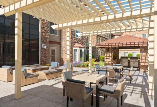 a patio with tables and chairs under a pergola at Homewood Suites by Hilton Portland Airport in Portland