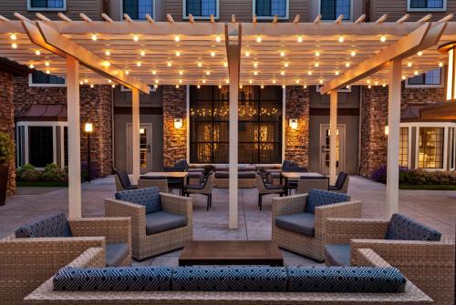 a patio with chairs and tables under a pergola with lights at Homewood Suites by Hilton Portland Airport in Portland