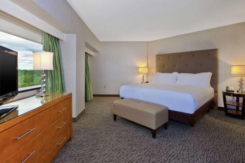 Embassy Suites by Hilton Auburn Hills في أوبورن هيلز: غرفة فندقية بسرير وتلفزيون بشاشة مسطحة