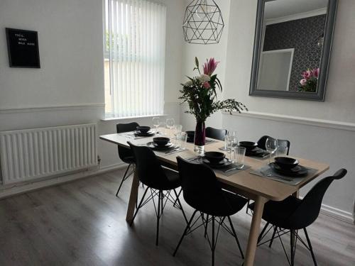 a dining room with a table with chairs and flowers at Antonio str Liverpool 6 beds in Liverpool