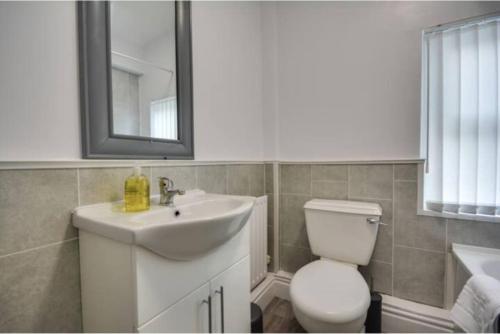a bathroom with a sink and a toilet and a mirror at Antonio str Liverpool 6 beds in Liverpool