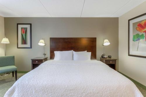 a bedroom with a large white bed and a chair at Hampton Inn Richmond - South in Richmond