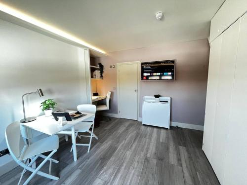 Habitación con mesa blanca, sillas y nevera. en Apt 12 Luxury Living Chic Studio Steps from Beach, en Brighton & Hove
