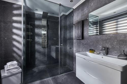 a bathroom with a glass shower and a sink at Domenico Homes - City Center in Heraklio