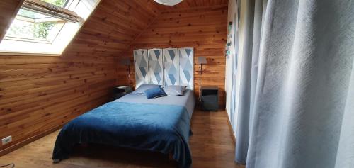 ein Schlafzimmer mit einem Bett in einer Holzhütte in der Unterkunft Maison de vacances La Valessoune in Valessard