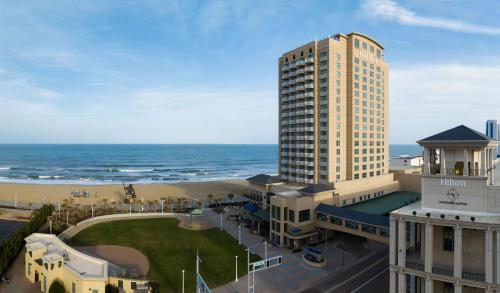 un grand bâtiment avec l'océan en arrière-plan dans l'établissement Hilton Virginia Beach Oceanfront, à Virginia Beach