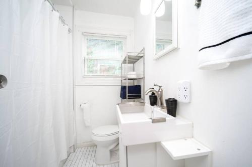 a white bathroom with a toilet and a sink at Trendy Apartment in Downtown - Near Montrose in Houston