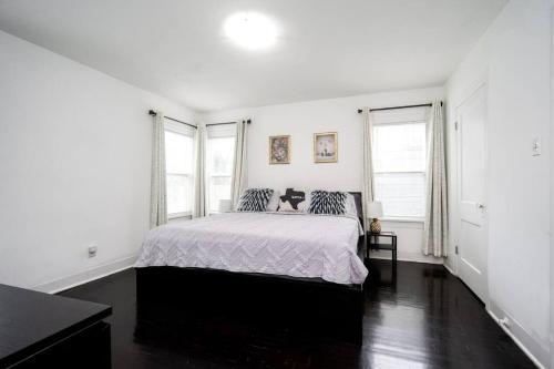 a white bedroom with a bed and two windows at Trendy Apartment in Downtown - Near Montrose in Houston