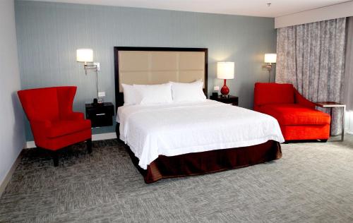 een slaapkamer met een bed en twee rode stoelen bij Hampton Inn- Suffolk in Suffolk