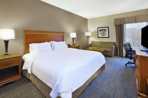 a hotel room with a large white bed and a desk at Hampton Inn Richmond-West Innsbrook in Broad Meadows