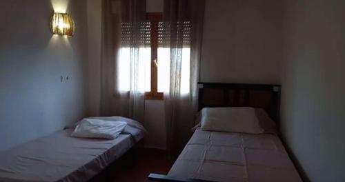 two beds in a small room with a window at Adosado en alquiler calle Penya el Figueret, 1 in Relleu
