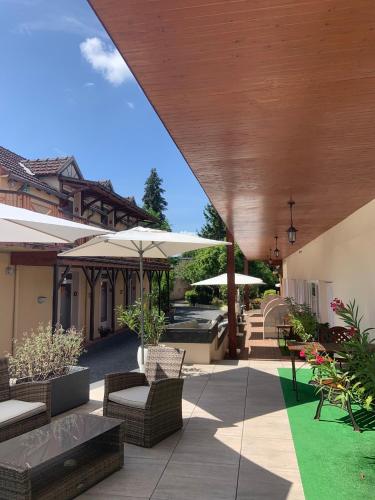 an outdoor patio with umbrellas and tables and chairs at The Originals Boutique, Hôtel Clos Sainte Marie, Nevers in Nevers