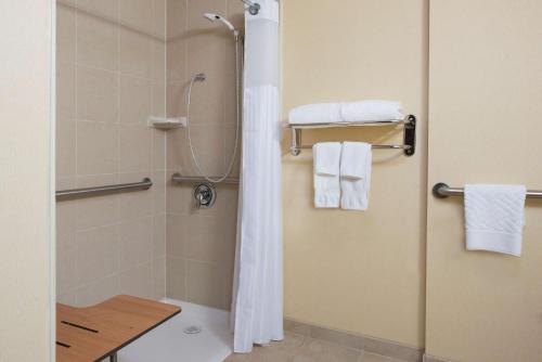 a bathroom with a shower with a toilet and towels at DoubleTree by Hilton Hotel Grand Rapids Airport in Grand Rapids