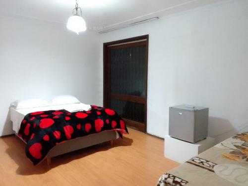 um quarto com uma cama com um cobertor preto e vermelho em Pousada A Cabana em Uruguaiana