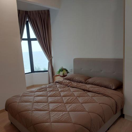 a bedroom with a large bed with a large window at Mutiara Melaka Beach Apartment in Melaka