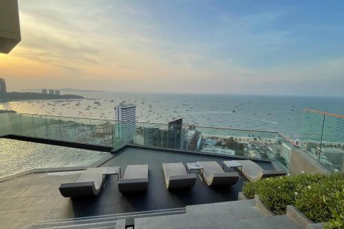 a group of benches on a balcony overlooking the ocean at Edge Seaside Luxury Stylish Condo steps away from beach in Pattaya Central