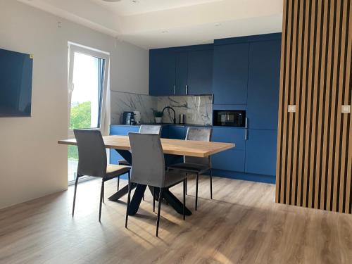 a kitchen with blue cabinets and a wooden table and chairs at Apartamenty A1 in Gdynia
