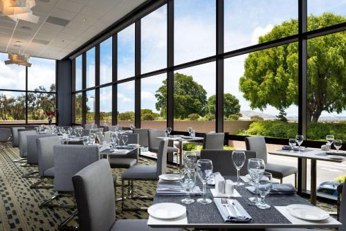 a restaurant with tables and chairs and large windows at Hilton San Francisco Airport Bayfront - No Resort Fee in Burlingame