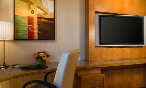 a room with a desk with a television and a chair at Hilton San Francisco Airport Bayfront - No Resort Fee in Burlingame