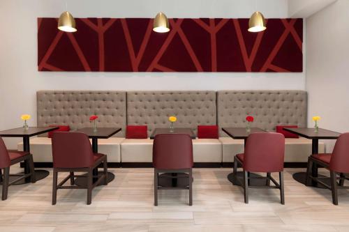a restaurant with two tables and red chairs at Hilton Garden Inn Long Island City in Queens