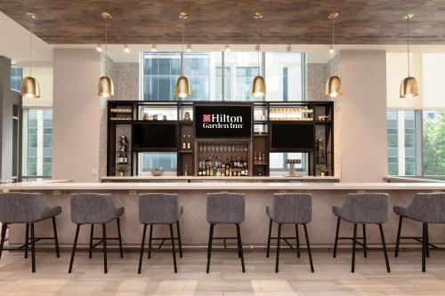 a bar in a hotel with chairs around it at Hilton Garden Inn Long Island City in Queens