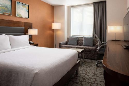 a hotel room with a bed and a desk and a television at Hilton Garden Inn Long Island City in Queens