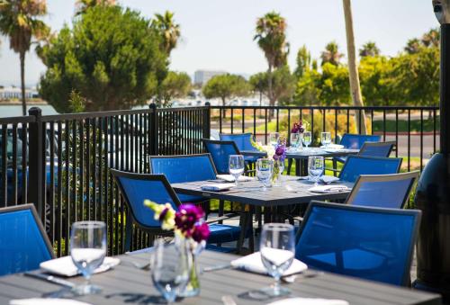 a row of tables with blue chairs and glasses at DoubleTree by Hilton San Francisco Airport North Bayfront in Brisbane