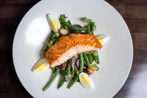 a white plate with a piece of fish and vegetables at DoubleTree by Hilton San Francisco Airport North Bayfront in Brisbane