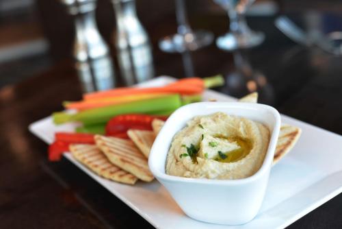 a white plate with dip and crackers and vegetables at DoubleTree by Hilton San Francisco Airport North Bayfront in Brisbane