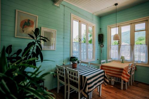 comedor con mesa, sillas y ventanas en Brotseulebi en Ambrolauri