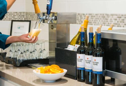 a person is making a drink in a kitchen with wine bottles at Homewood Suites by Hilton-Anaheim in Anaheim