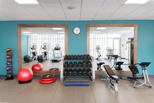 a gym with exercise equipment and a clock on the wall at Homewood Suites by Hilton Aliso Viejo Laguna Beach in Aliso Viejo