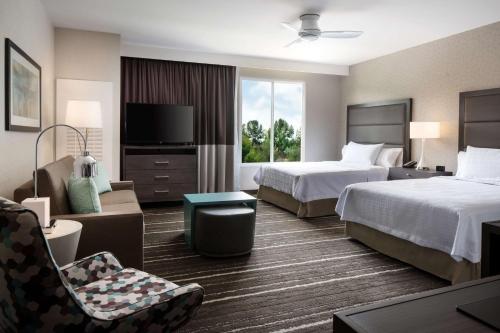 a hotel room with two beds and a chair at Homewood Suites by Hilton Aliso Viejo Laguna Beach in Aliso Viejo