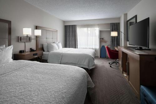 a hotel room with two beds and a flat screen tv at Hampton Inn & Suites Anaheim Garden Grove in Anaheim