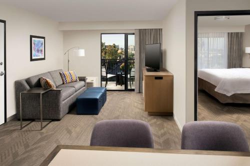 a hotel room with a couch and a bed and a television at Hampton Inn & Suites Anaheim Garden Grove in Anaheim
